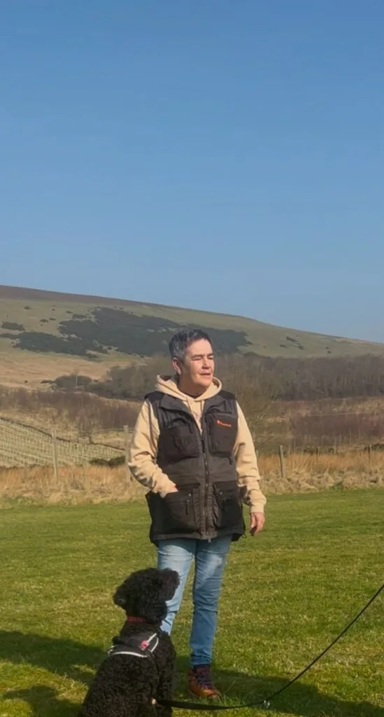 Dog walking calmly beside Pauline on leash during training walk